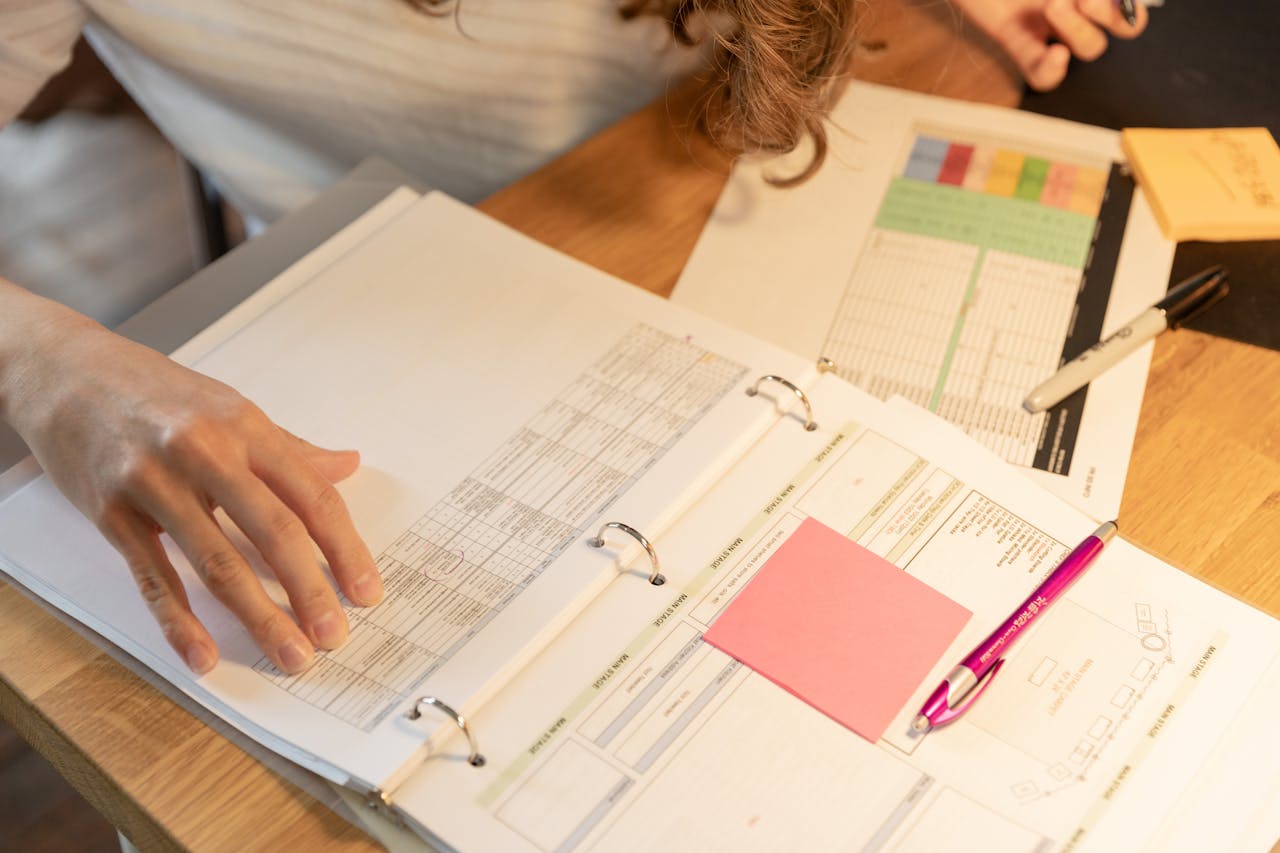 Mastering the First Impression: Your intriguing post title goes here Close-up of an employee sorting documents with sticky notes and pens on a wooden desk.